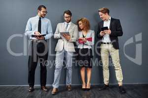 Its almost that time...Full length shot of a group of businesspeople using tablets and notebooks while waiting in line for a job interview.