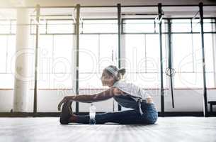 Stretching my legs for the intense workout coming up. an attractive young woman stretching at the gym.