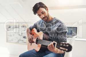 When words fail, music speaks. a handsome young man practising guitar at home.