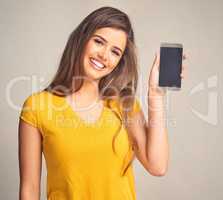 Ive a huge amount of space on this tiny device. an attractive young woman holding a cellphone with a blank screen against a grey background.