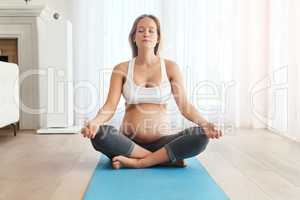 Meditation keeps her prepared for birth. a pregnant woman meditating on an exercise mat at home.