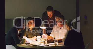 Sometimes the deadline dictates your work hours. a group of businesspeople working together around a table in their office.