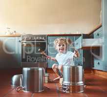 He wants to be a drummer when he grows up. Portrait of an adorable little boy playing with pots in the kitchen.