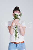 Let your dreams blossom. Studio shot of an unrecognizable woman covering her face with flowers against a grey background.