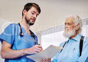 Lets first have a quick look at your results. a young doctor going through medical records with a senior patient at a hospital.