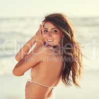 Playing the seaside siren. Portrait of a beautiful young woman in a white bikini posing on the beach.