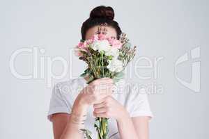Flowers reflect who we are. Studio shot of an unrecognizable woman covering her face with flowers against a grey background.
