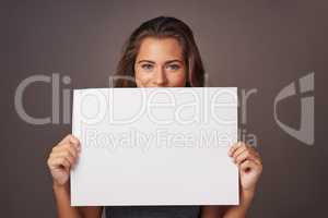 I have a statement to make. Studio shot of an attractive young woman holding a blank placard against a gray background.