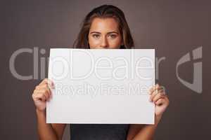 Stop scrolling. This is way more interesting. Studio shot of an attractive young woman holding a blank placard against a gray background.