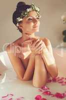 You never need an excuse to spoil your skin. Portrait of a beautiful nude woman relaxing in a bathtub filled with milk and flower petals at home.