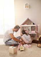 Connecting with her at her level. Full length shot of a handsome young man and his daughter playing with her dollhouse.