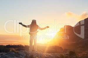 Chasing the sun. a hiker with his arms raised standing on top of a mountain.