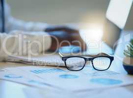 Keep success clearly in sight. a pair of spectacles on a table with an unrecognisable businessman working in the background.