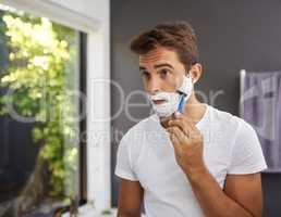 Time to say goodbye facial hair. a handsome man shaving his beard in the bathroom at home.