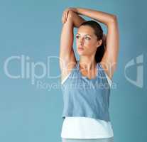 Warming up her muscles. Studio shot of a healthy young woman warming up against a blue background.