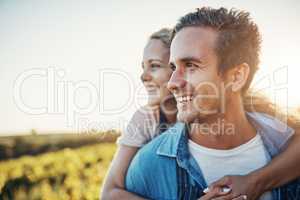 They love owning this farm. a handsome young man piggybacking his girlfriend through the crops on their farm.