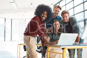 Were ready to get to work. Portrait of a team of happy designers working around a laptop in their modern office.