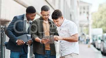 Team of creative designers checking a website for ux and ui while working for a startup. Group of young guys looking at a homepage on a tablet while developing a new business strategy or mission