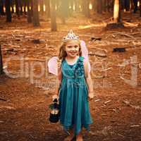 Im a real life fairy. a happy little girl looking at the camera and holding a lamp while standing outside in the woods.
