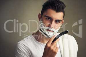 Be kinder to your skin. a handsome young man shaving with a straight razor.