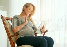 Connecting with other expectant parents. a pregnant woman using her digital tablet while sitting on a rocking chair.