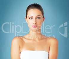 Giving her beauty routine the seriousness it deserves. Studio portrait of a beautiful young woman posing against a blue background.