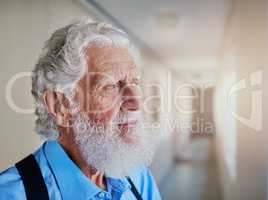 Lost in nostalgia. a senior man looking thoughtful while standing in the hallway of his nursing home.