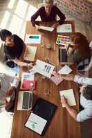 Working in a cooperative environment. High angle shot of a group of colleagues having a meeting in a modern office.