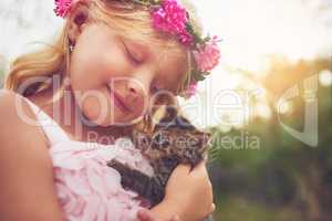 My furry friend. a happy little girl holding a kitten and smiling while sitting outside in nature.
