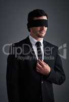 Is your lack of vision limiting you. Studio shot of a young businessman wearing a blindfold against a gray background.