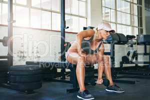 Looking like a beauty while training like a beast. a sporty young woman lifting weights at the gym.