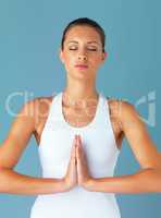 Inner strength comes from a calm mind. Studio shot of a fit young woman meditating against a blue background.