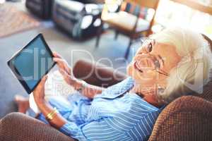 Technology is for anyone at any age. a senior woman using a tablet at home.