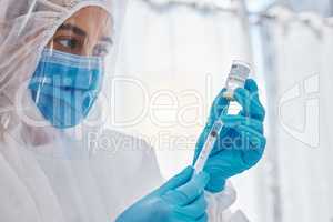 Medical scientist, doctor or healthcare worker in a safety suit ready to give the covid vaccine. Hospital employee holding, looking and working with care on a corona medicine vial at a hospital