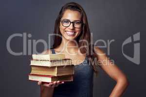 If you think reading is boring, youre doing it wrong. Studio portrait of a young woman holding a pile of books against a grey background.