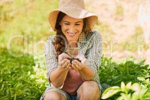 New life is beautiful to behold. a happy young farmer holding a pile of soil with a seedling growing out of it outside.