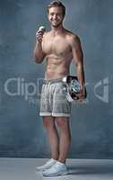 Im in the best shape of my life. Portrait of a healthy young man eating an apple while posing with a scale in studio.