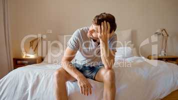 Depression, mental health and sad man in stress feeling bad, upset and depressed alone in his home, house or hotel suite. Wake up, morning and frustrated, unhappy male in bedroom tired with anxiety