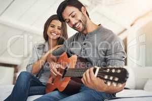 I could listen to him play all day. an attractive young couple spending quality time at home.
