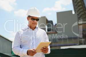 The tablet makes his work life a bit more simple. a professional male architect on a building site while working on a digital tablet outside.