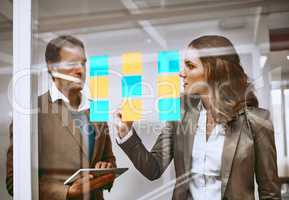 She has an idea. two businesspeople working on a glass wipe board in their office.