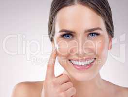 Moisturizing makes everything better. Studio shot of a beautiful young woman applying moisturizer to her face against a grey background.