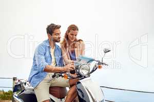 Taking a trip on two wheels. an affectionate couple looking at a map while out on their motorcycle.