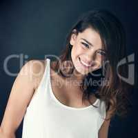 Her smile only adds to her beauty. a beautiful young woman posing in the studio.