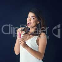 Ladies you have to get them lips right. Studio shot of a beautiful young woman applying lip gloss against a grey background.