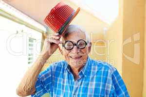 I take my hat off to you sir. a carefree elderly man wearing funky glasses and a hat while posing for the camera inside a building.