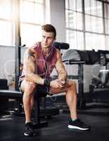During my workout I like to take a moment to rest. a handsome young man taking a break during his workout at the gym.
