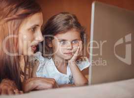 Engaged with the online world. a mother and her little daughter using a laptop together at home.