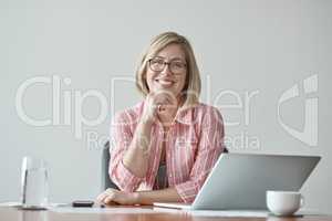 I firmly believe Ive got what it takes. Studio portrait of a confident businesswoman sitting at a desk against a grey background.