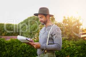 The admin side of farming. a young man checking the stock in his garden.